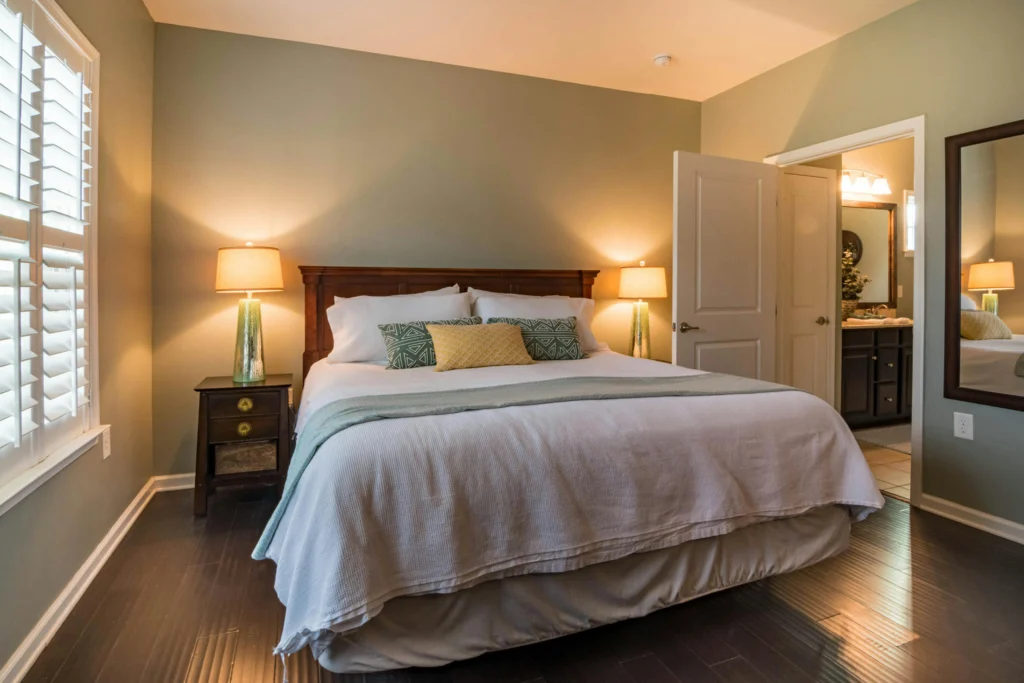 Image of bedroom with dark wood furniture, soft lighting, patterned pillows.